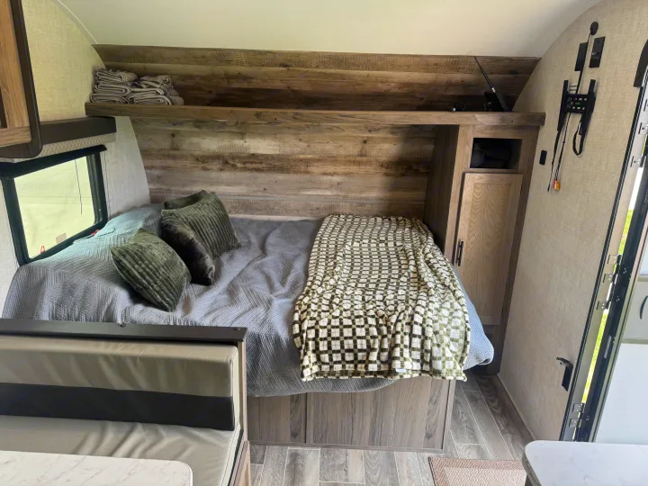 Cozy RV rental bedroom with a comfy bed, patterned blanket, wood accents, and built-in storage shelves.. Gulf Stream Ameri-Lite Super Lite 2022