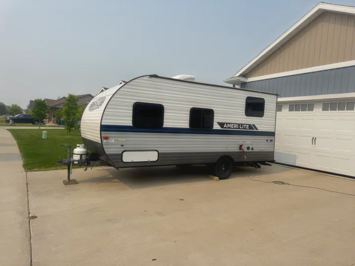 Light gray Ameri Lite travel trailer, ready for your next RV rental adventure, parked in a residential driveway.. Gulf Stream Ameri-Lite Super Lite 2022