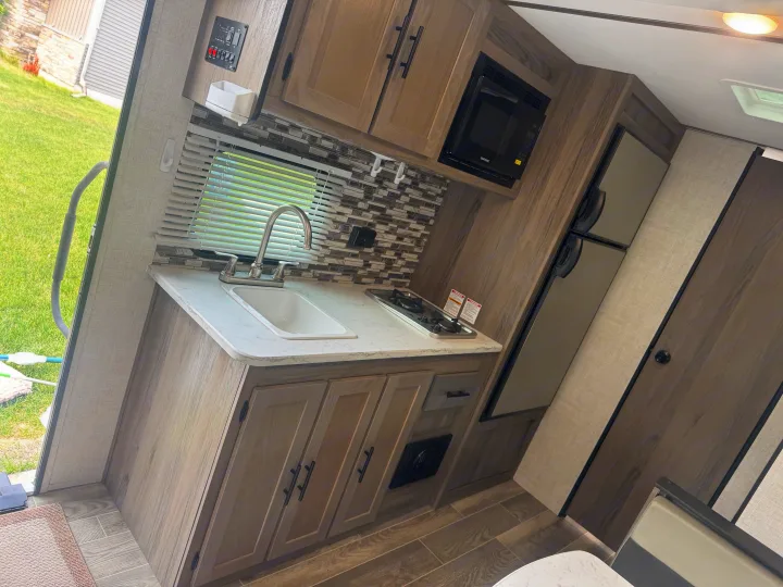 Interior view of an **rv rental** kitchen, highlighting the sink, stovetop, microwave, and fridge for comfortable trips.. Gulf Stream Ameri-Lite Super Lite 2022
