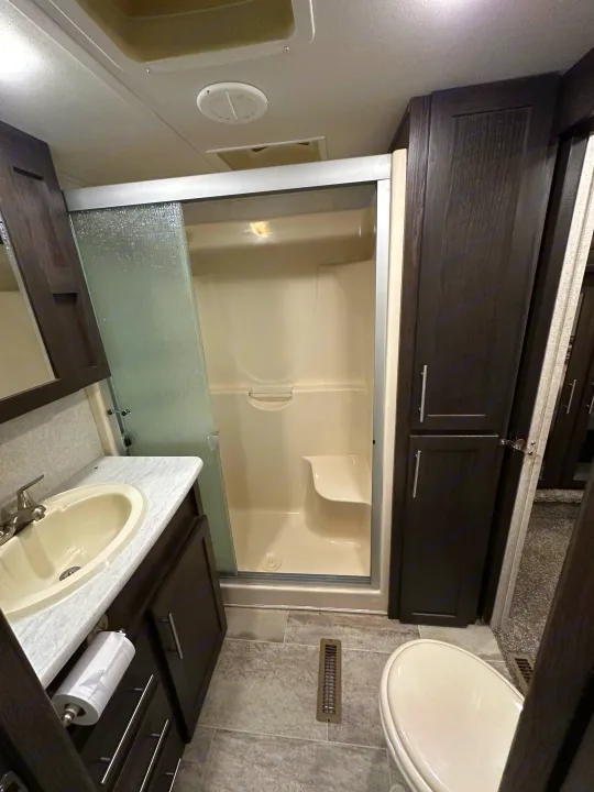 Modern RV rental bathroom showcasing a clean shower, vanity sink, and toilet. Ideal for comfortable travels.. Keystone RV Carbon Toy Hauler 2018