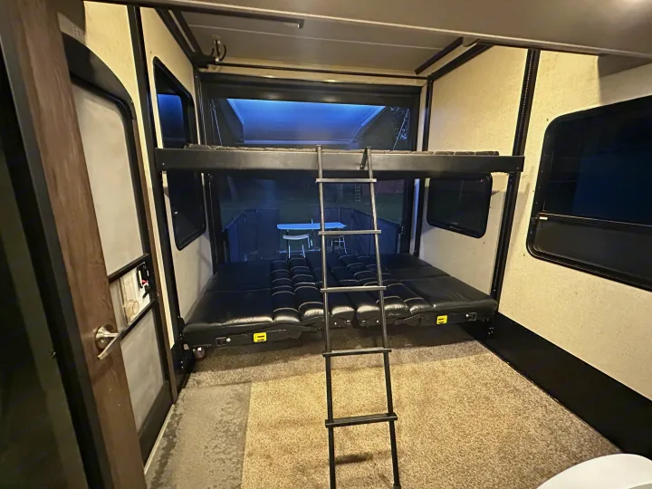 RV rental toy hauler interior. The garage area features adjustable bunk beds and a ladder, with the rear ramp open to the outside.. Keystone RV Carbon Toy Hauler 2018