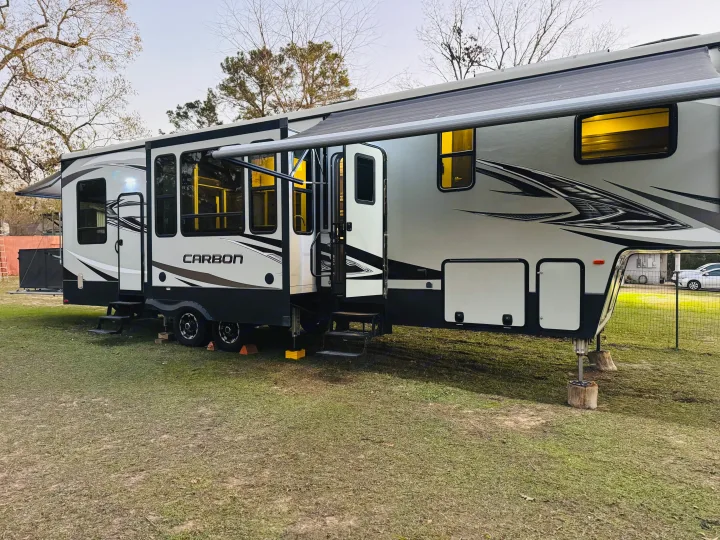 A large Carbon fifth-wheel RV rental is parked, fully set up with awning extended for a comfortable outdoor stay.. Keystone RV Carbon Toy Hauler 2018