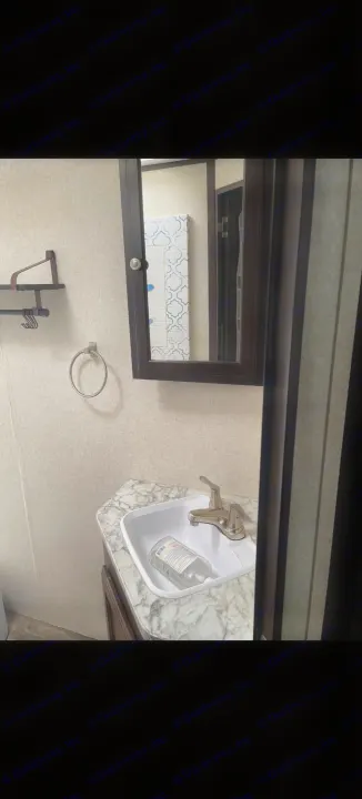This RV rental bathroom offers a compact sink with hand sanitizer, a medicine cabinet mirror, and wall storage.. Jayco Jay Flight 2018