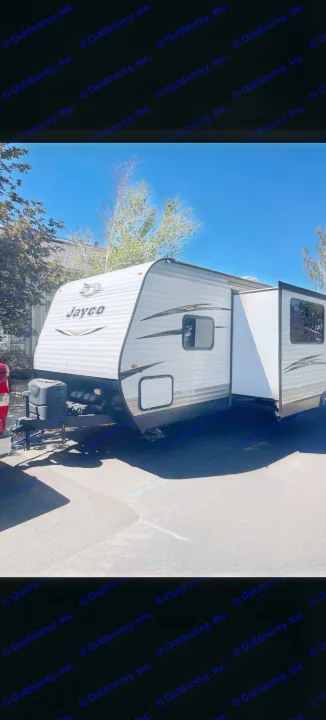 White Jayco travel trailer with slide-out extended, perfect for your next rv rental. RV parked on asphalt on a sunny day.. Jayco Jay Flight 2018