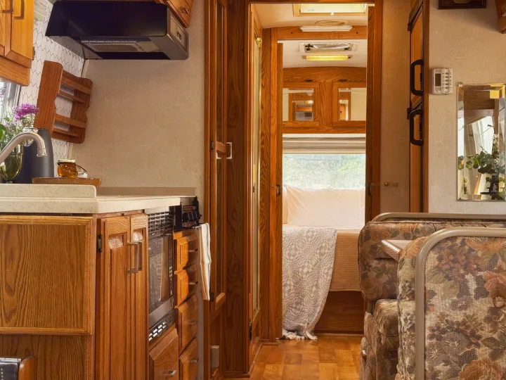 This RV rental offers a well-equipped kitchen, a comfortable bedroom, and a cozy floral living area.. Airstream Classic 2002