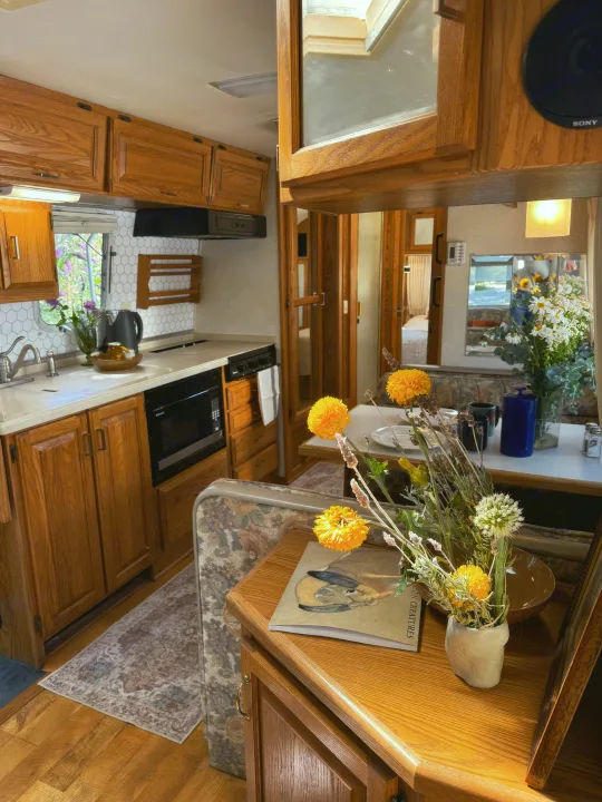 Inviting RV rental interior: bright kitchen, cozy dining area with flowers, and warm wooden accents.. Airstream Classic 2002