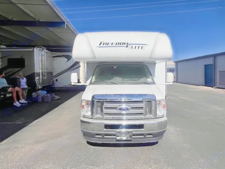 Front view of a white Freedom Elite RV rental, a Class C motorhome, parked on a sunny day.. Thor Freedom Elite 2022