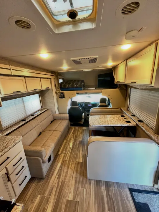 Bright RV rental interior featuring a lounge, dining area, overhead bunk, and kitchenette. Ideal for comfortable travel.. Thor Freedom Elite 2022