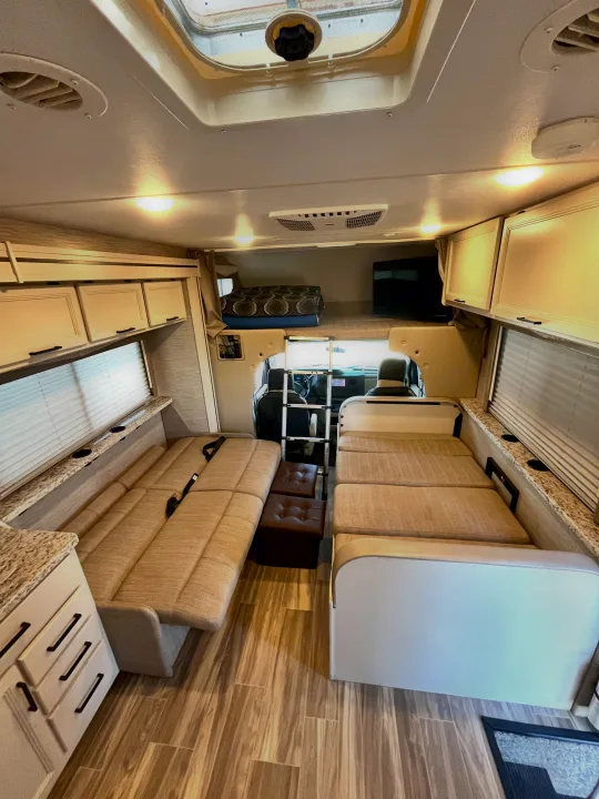 RV rental interior: A bright, inviting living space with dinette seating, overhead storage, and a comfy cab-over bunk bed.. Thor Freedom Elite 2022