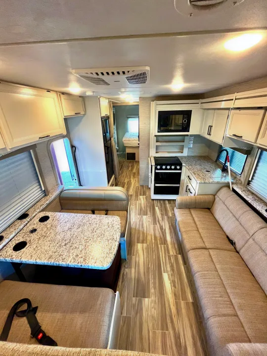 RV rental: Interior of modern RV with light wood-look floor, dinette, sofa, kitchen, and bedroom access.. Thor Freedom Elite 2022