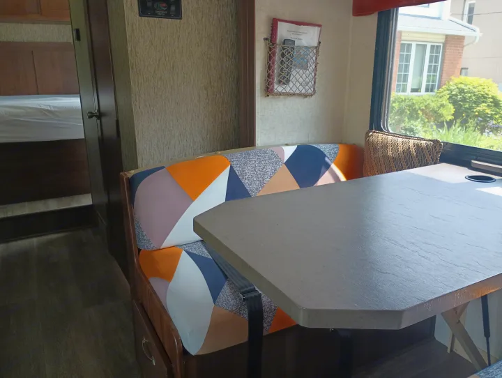 Cozy RV rental interior: dinette with vibrant geometric cushions, sturdy table, and adjacent bedroom view.. Forest River Sunseeker 2018