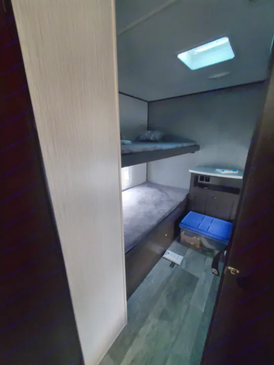 This RV rental offers a practical interior with cozy bunk beds, a window, and a storage cabinet, ideal for a compact space.. Heartland RVs Prowler 2021