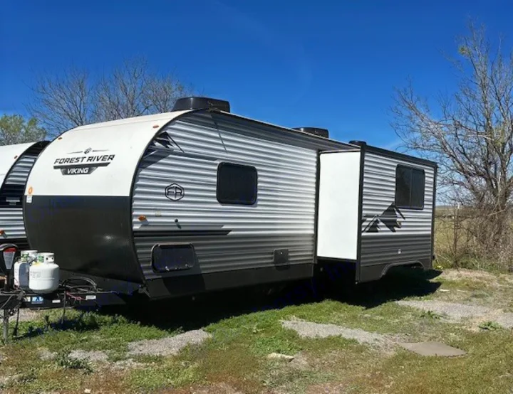 Forest River Viking travel trailer, an RV rental with its slide-out extended, parked under a clear sky.. Forest River Forest River Viking 2025