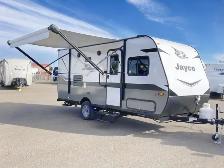 White & gray Jayco travel trailer with awning extended, perfect for an RV rental getaway.. Jayco Jay Flight SLX 2022
