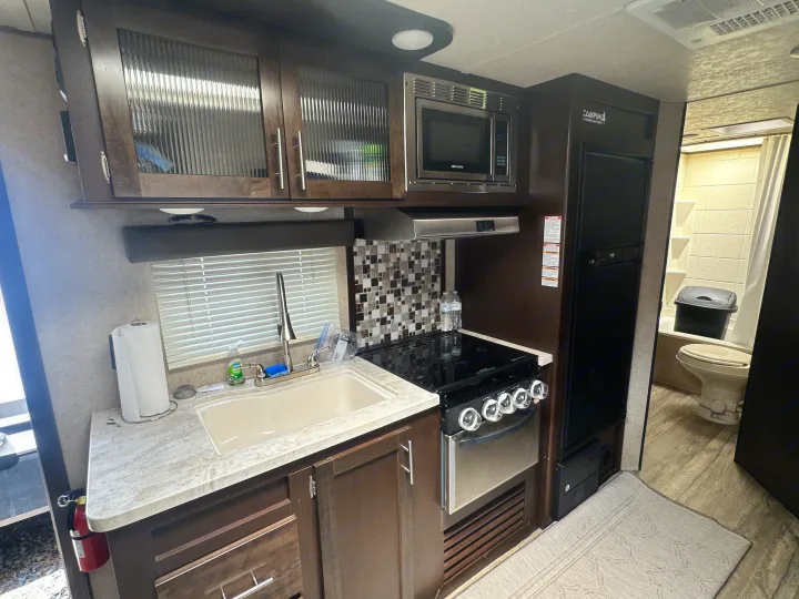 Modern RV rental interior with full kitchen (sink, stove, microwave, fridge) and accessible bathroom.. Forest River Cherokee Grey Wolf 2017