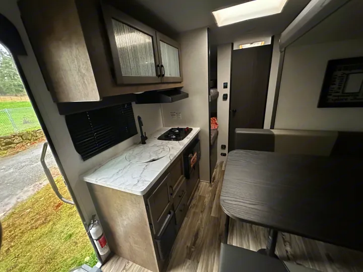 Inside an rv rental, highlighting the functional kitchen with sink & stovetop, and comfortable dining area for compact living.. Venture RV SL169VUD 2023