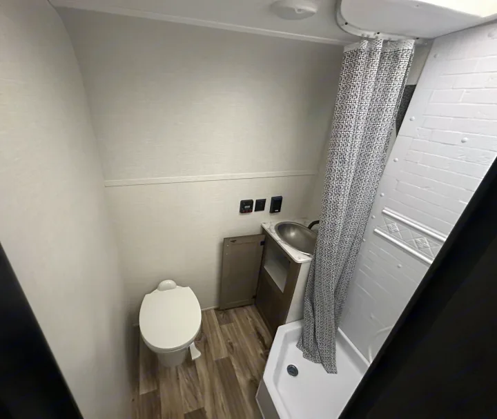 Clean & modern RV rental bathroom: toilet, vanity with sink, and shower. Perfect for travel comfort.. Venture RV SL169VUD 2023