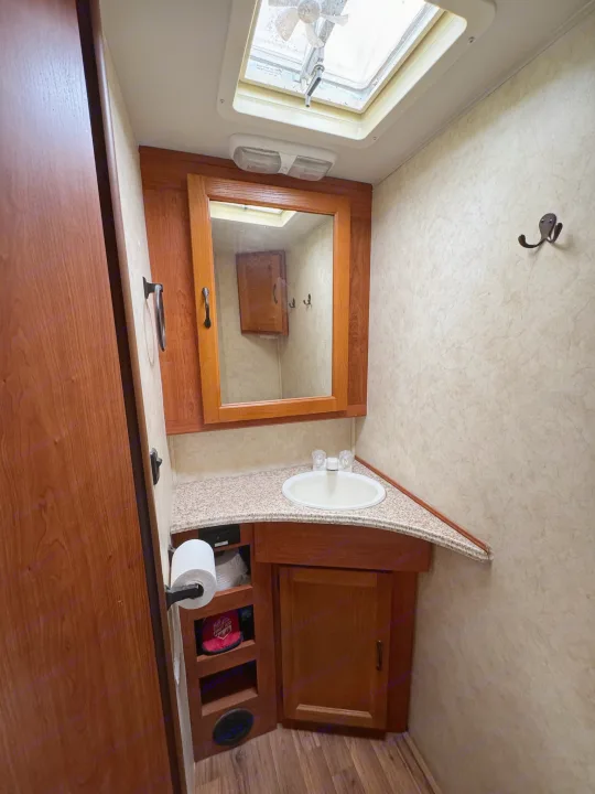 Our RV rental offers a well-equipped, compact bathroom with a sink, mirror, toilet paper, storage, and skylight.. Coachmen Freelander 2014