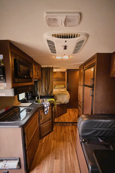 Interior of a modern RV rental, featuring a full kitchen, cozy bedroom, and comfortable living space.. Thor Majestic 2018