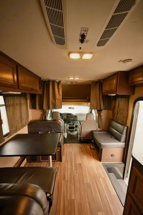 Spacious RV rental interior: comfortable dinette, functional cockpit, ample storage, and stylish wood-look floors.. Thor Majestic 2018