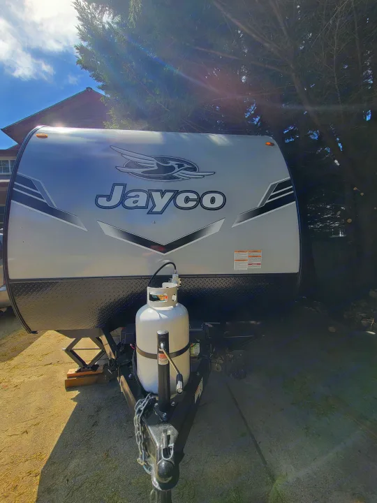 Detailed front view of a silver Jayco travel trailer, ready for rv rental, showing its propane tank and front jack.. Jayco Jay Flight SLX 197MBW Baja Edition 2025