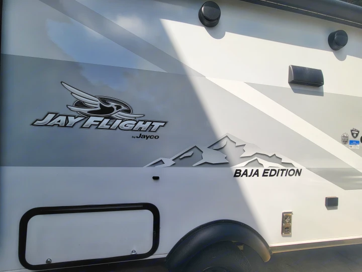 White Jayco Jay Flight Baja Edition RV side, featuring mountain graphics and storage hatch. Perfect for your RV rental.. Jayco Jay Flight SLX 197MBW Baja Edition 2025