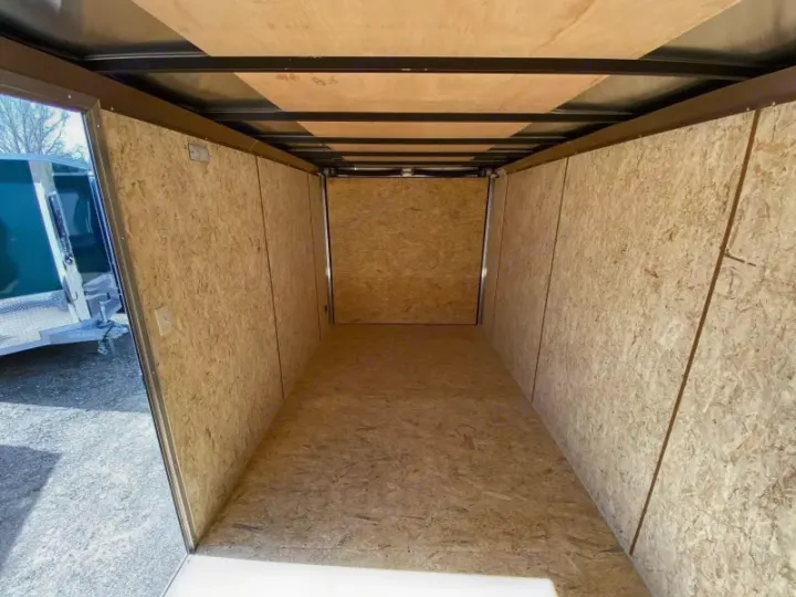 Empty enclosed cargo trailer interior with wood-composite (OSB) walls, floor, and ceiling, ready for RV rental transport.. ITI Cargo 7X14 2025