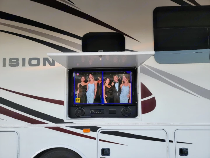 RV rental with outdoor TV display. Enjoy entertainment on the go, showing a group of people from ET.. Entegra Coach Vision 2019