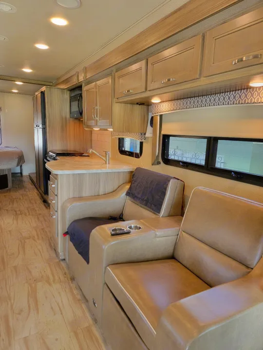 Spacious RV rental interior: modern kitchen, comfy recliners, wood flooring, and ample storage.. Entegra Coach Vision 2019
