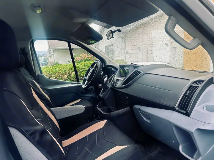 Experience comfort in this van's interior, ideal for your RV rental journey. Features driver's area, dash, and rainy windshield.. FORD TRANSIT 250 2015