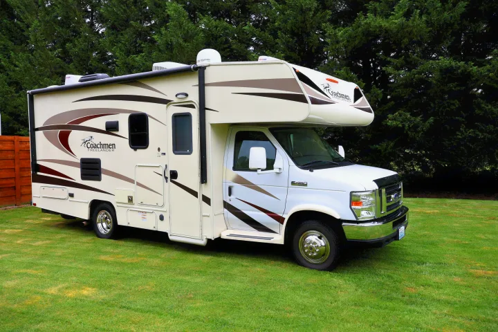 White and beige Coachmen Freelander Class C RV rental parked on a green lawn, trees in background.. Other Freelander 2016