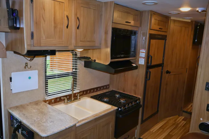Compact RV rental kitchen with sink, stove, microwave, and fridge. Ideal for road trips.. Other Freelander 2016