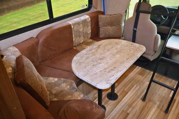 Cozy RV rental interior: L-shaped dinette seating, stone-look table, scenic window views, & forward cabin.. Other Freelander 2016