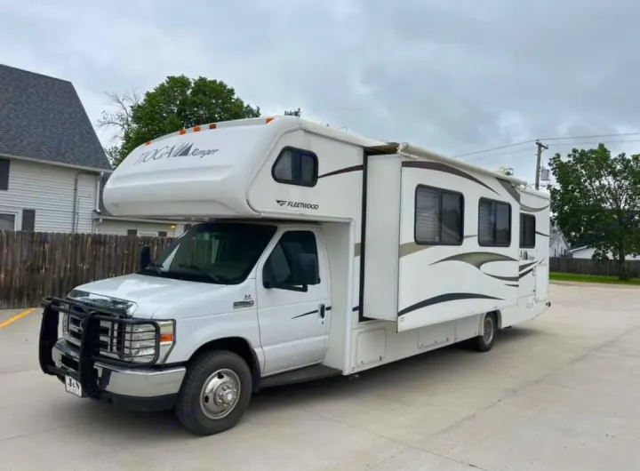 White Fleetwood Tioga Ranger Class C RV rental, parked on pavement. Features a slide-out and front brush guard.. Tioga Tioga Motorhome 2009