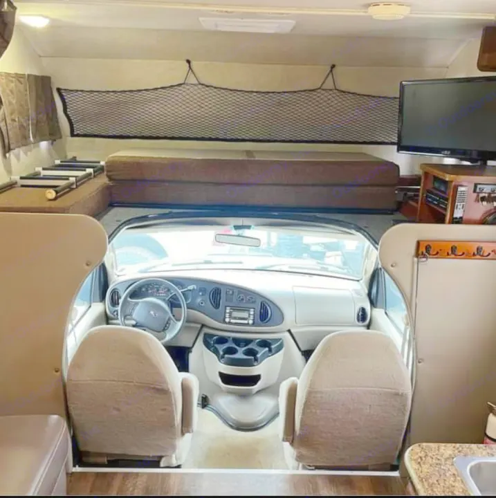Inside a comfy **rv rental**, featuring the driver's cab, a large overhead bed, and a glimpse of the kitchen. Ready for the open road.. Tioga Tioga Motorhome 2009