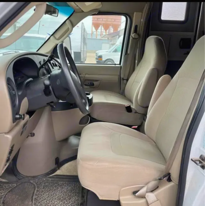 Spacious front cabin of an RV rental van, showing beige seats, steering wheel, and dashboard. Ready for comfortable travel.. Tioga Tioga Motorhome 2009