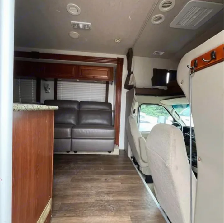 Spacious RV rental interior featuring a comfortable living area with couch, wooden cabinets, and front cabin seats. Perfect for your next adventure!. Tioga Tioga Motorhome 2009