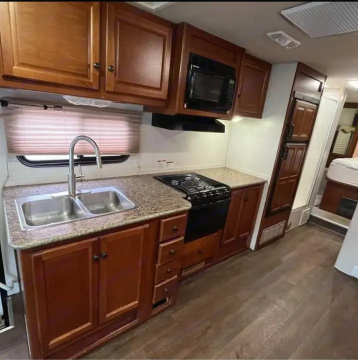 Inside an RV rental kitchen: Sink, stove, microwave, fridge, and ample cabinets for travel cooking.. Tioga Tioga Motorhome 2009