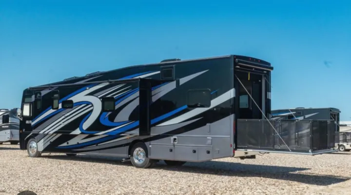 This black and blue toy hauler RV rental features a spacious rear patio, ideal for adventure travels.. Thor Outlaw 2022