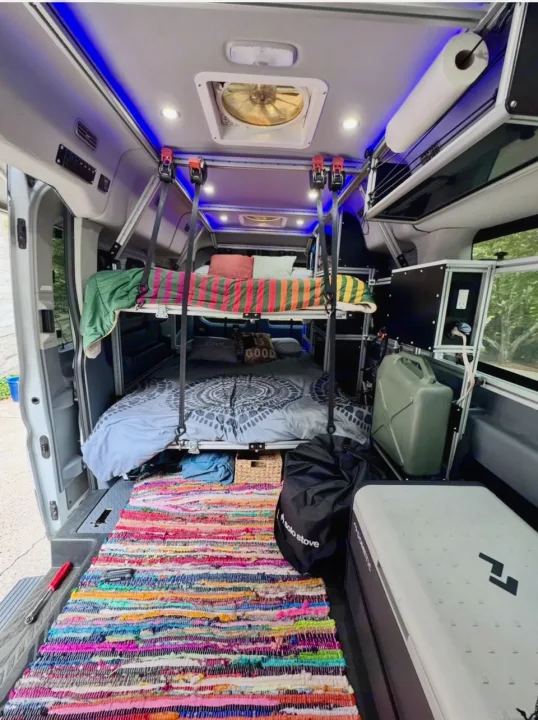 Cozy RV rental camper van interior with bunk beds, organized storage, and colorful rug. Perfect for mobile living.. Ford Transit 2017