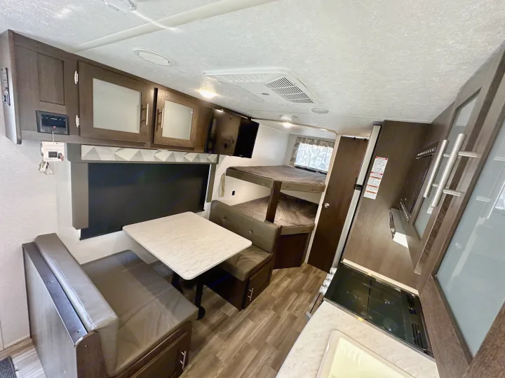 Spacious RV rental interior with dinette, bunk beds, kitchen, and entertainment system for comfortable travel.. Forest River Wildwood X-Lite 2020