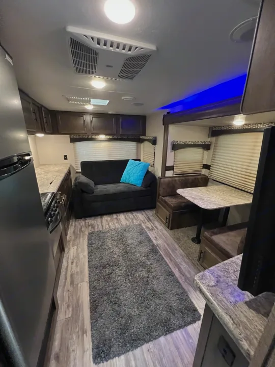Spacious RV rental interior: features living area with sofa, kitchen, dinette, wood-look floor, gray rug, and blue accent lighting.. KZ Connect RLK 24 2019