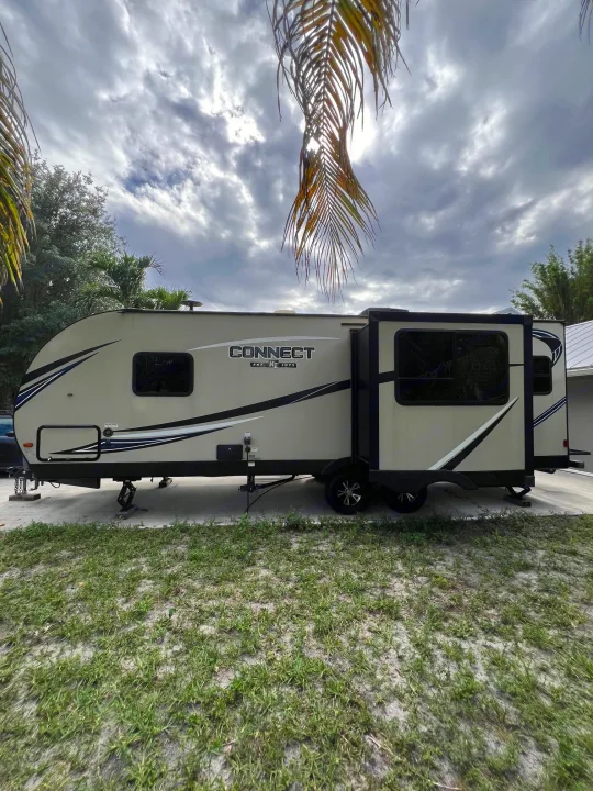 A beige travel trailer with slide-out extended, parked on a paved driveway under a cloudy sky. Ideal rv rental.. KZ Connect RLK 24 2019