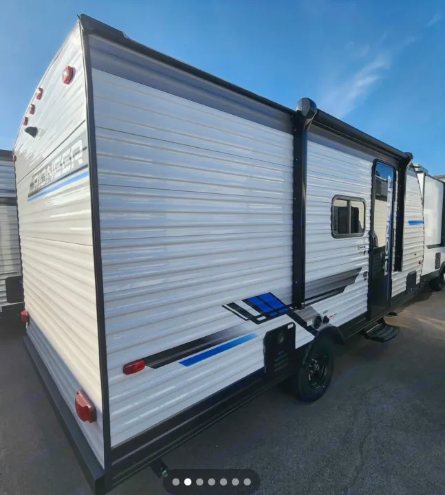 Light grey Pioneer travel trailer with blue accents, ideal for RV rental. Features an awning, ready for your camping adventures.. Heartland Pioneer 2025