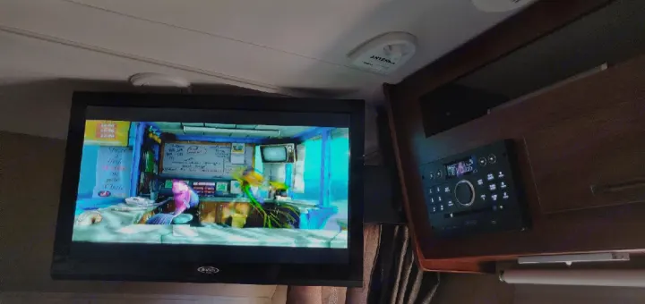 Inside an RV rental: Flat-screen TV displaying animated content, with a built-in stereo and overhead antenna.. Forest River Forester 2017
