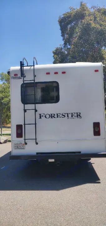 Rear of a white Forester RV rental, featuring a ladder, window, taillights, and license plate.. Forest River Forester 2017