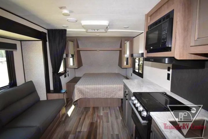 Inside an RV rental: a compact interior features a bed, kitchen with stove and microwave, and a small sofa. Modern design.. Starcraft Autumn Ridge 20FBS 2022