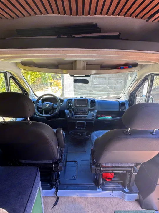 RV rental. Interior view of a camper van's front cabin: dashboard, steering wheel, and seats.. Dodge B Van 2023