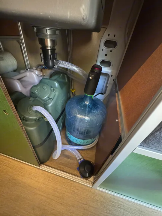 RV rental's under-sink water system: fresh water bottle, waste tank, and pumps for efficient mobile living.. Dodge B Van 2023