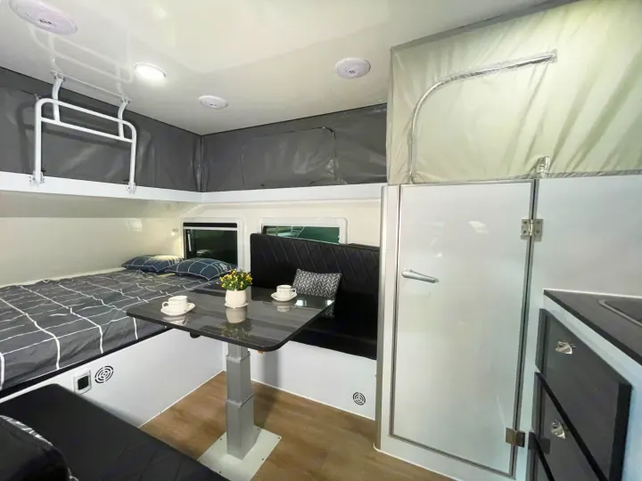 Cozy compact RV rental interior featuring a pop-top roof, comfortable bed, and functional dining area.. Zoomies Campers Eagle’s Nest 2025